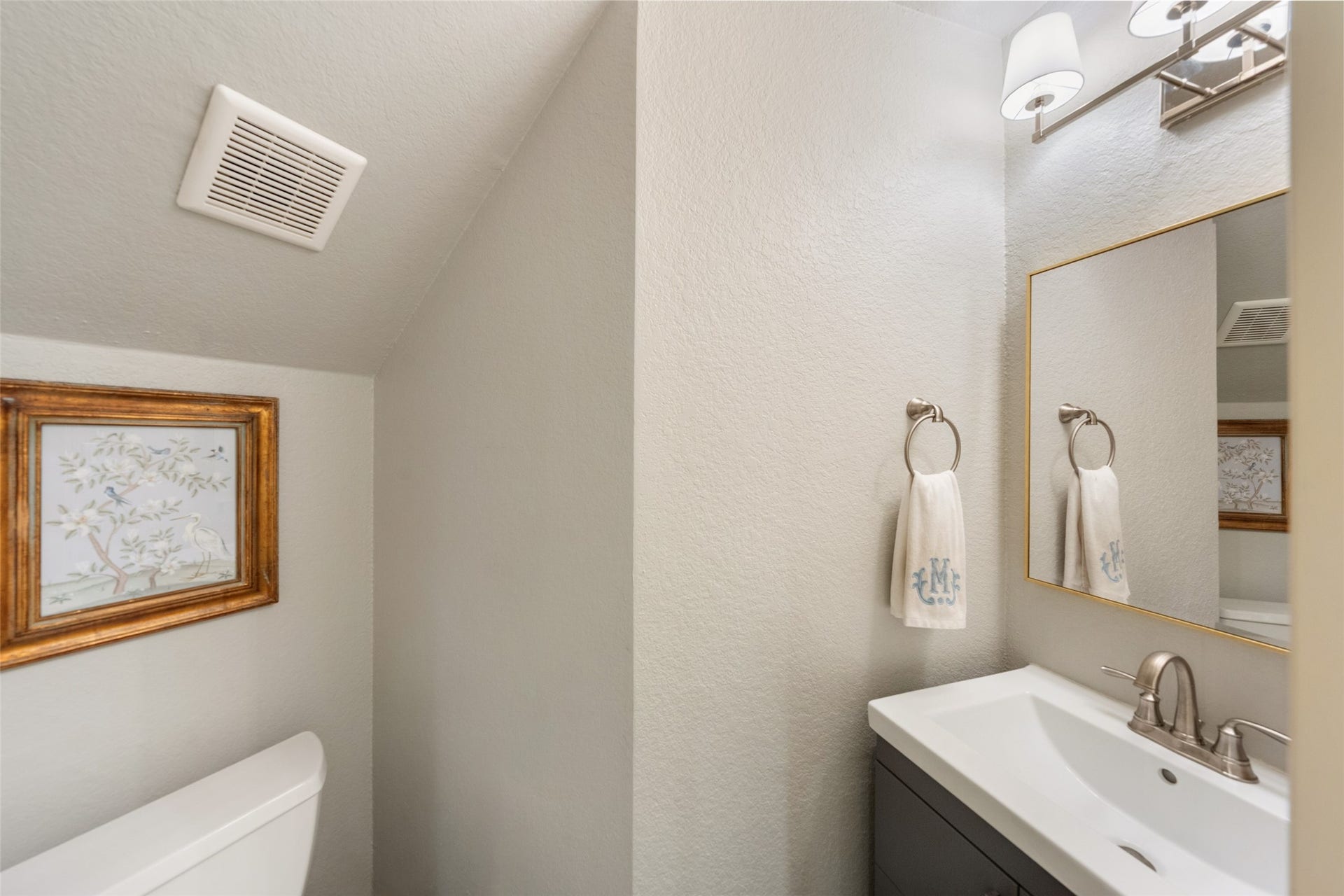 34 Alderon Woods Place, The Woodlands, TX 77382 Charming powder room with modern fixtures, elegant wall art, and a sleek vanity, creating a cozy and stylish space.