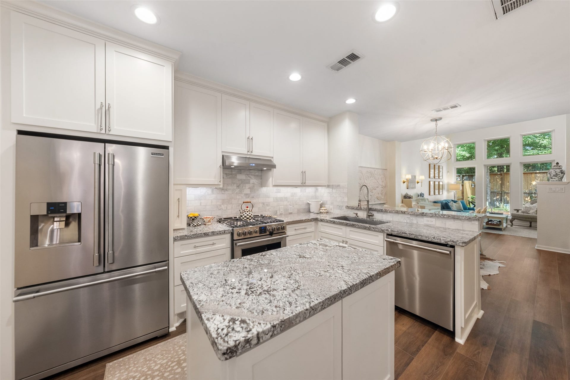 34 Alderon Woods Place, The Woodlands, TX 77382 Modern kitchen with sleek stainless steel appliances, elegant granite countertops, and an open layout leading to a bright living area with large windows.