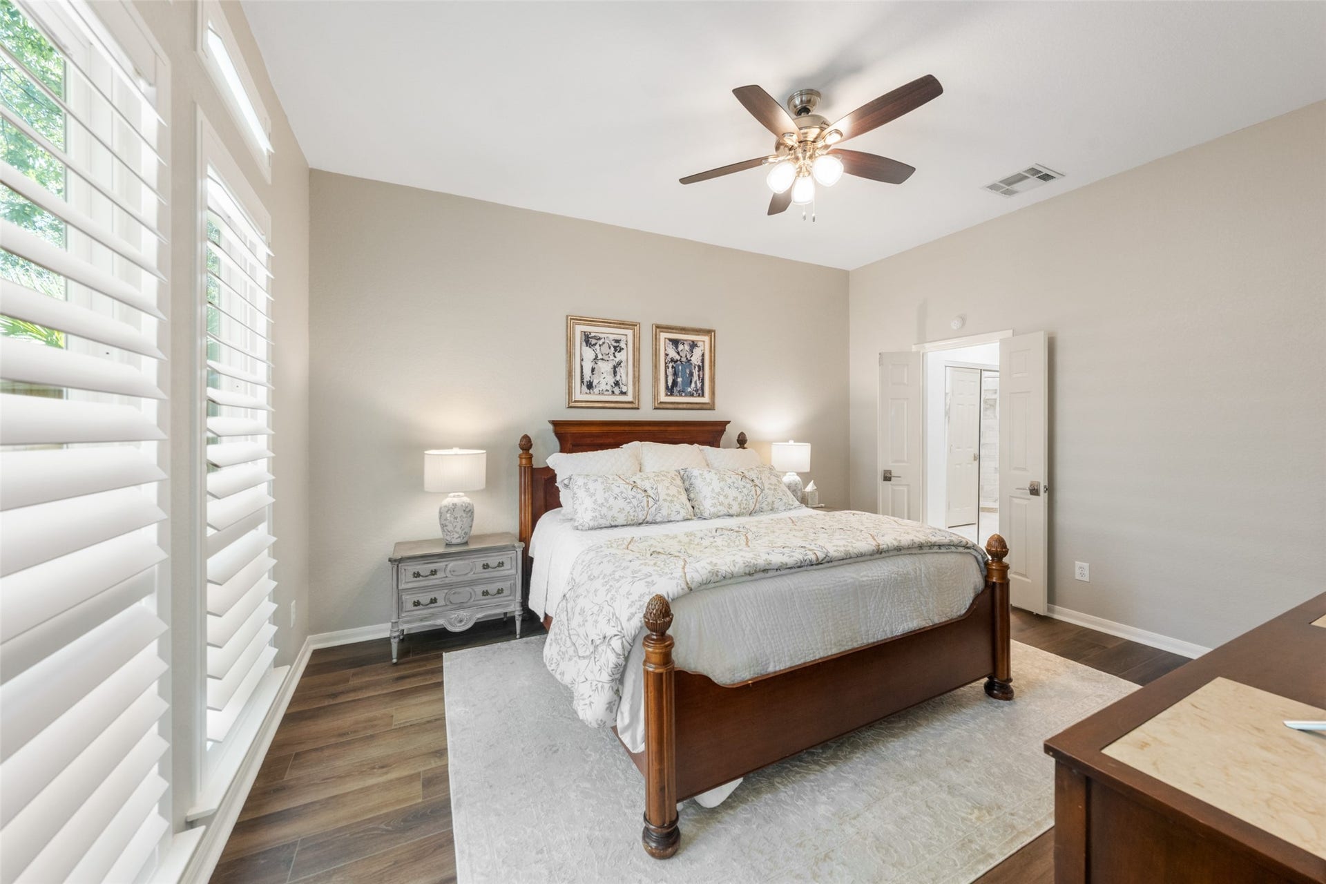 34 Alderon Woods Place, The Woodlands, TX 77382 Spacious bedroom with elegant floors, abundant natural light from large windows, and a cozy atmosphere featuring classic neutral tones.