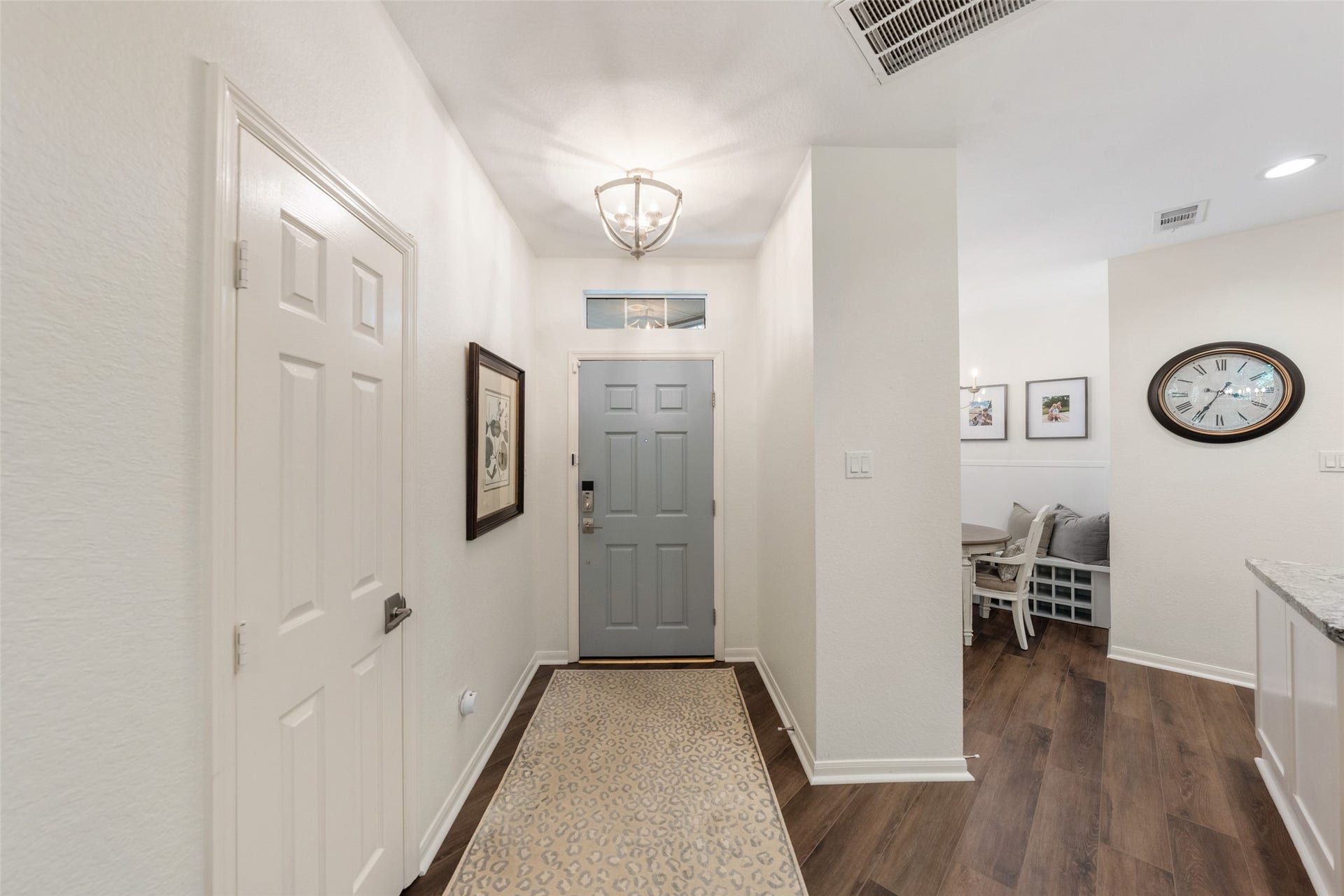 34 Alderon Woods Place, The Woodlands, TX 77382 Inviting entryway with elegant lighting, warm LVP flooring, and a stylish blue front door, leading to a cozy dining area.