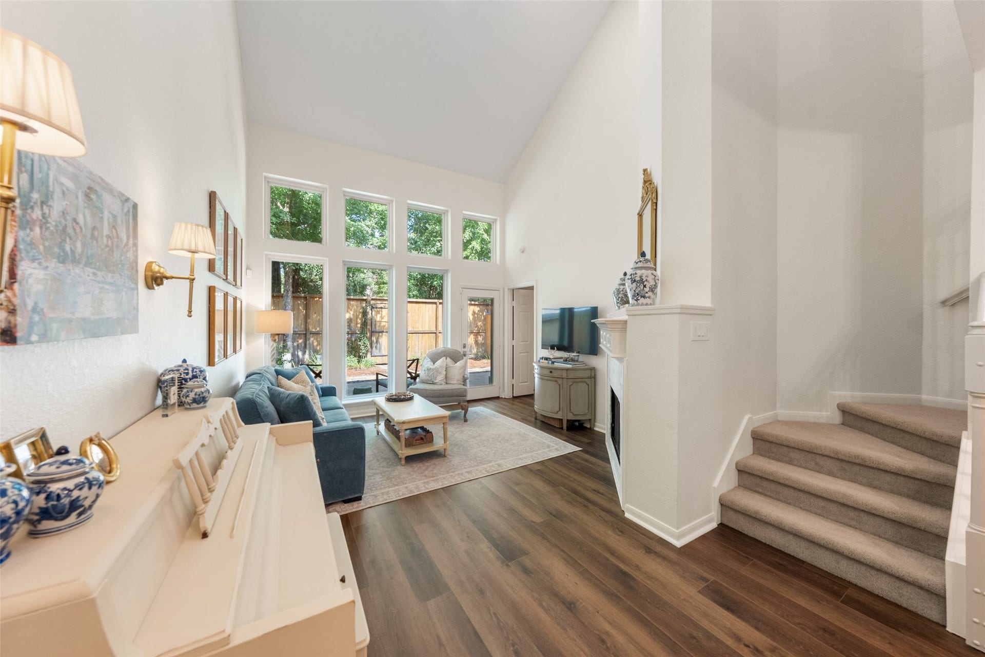34 Alderon Woods Place, The Woodlands, TX 77382 Expansive living room with soaring ceilings, abundant natural light from large windows, and elegant LVP flooring, offering a warm and inviting space.
