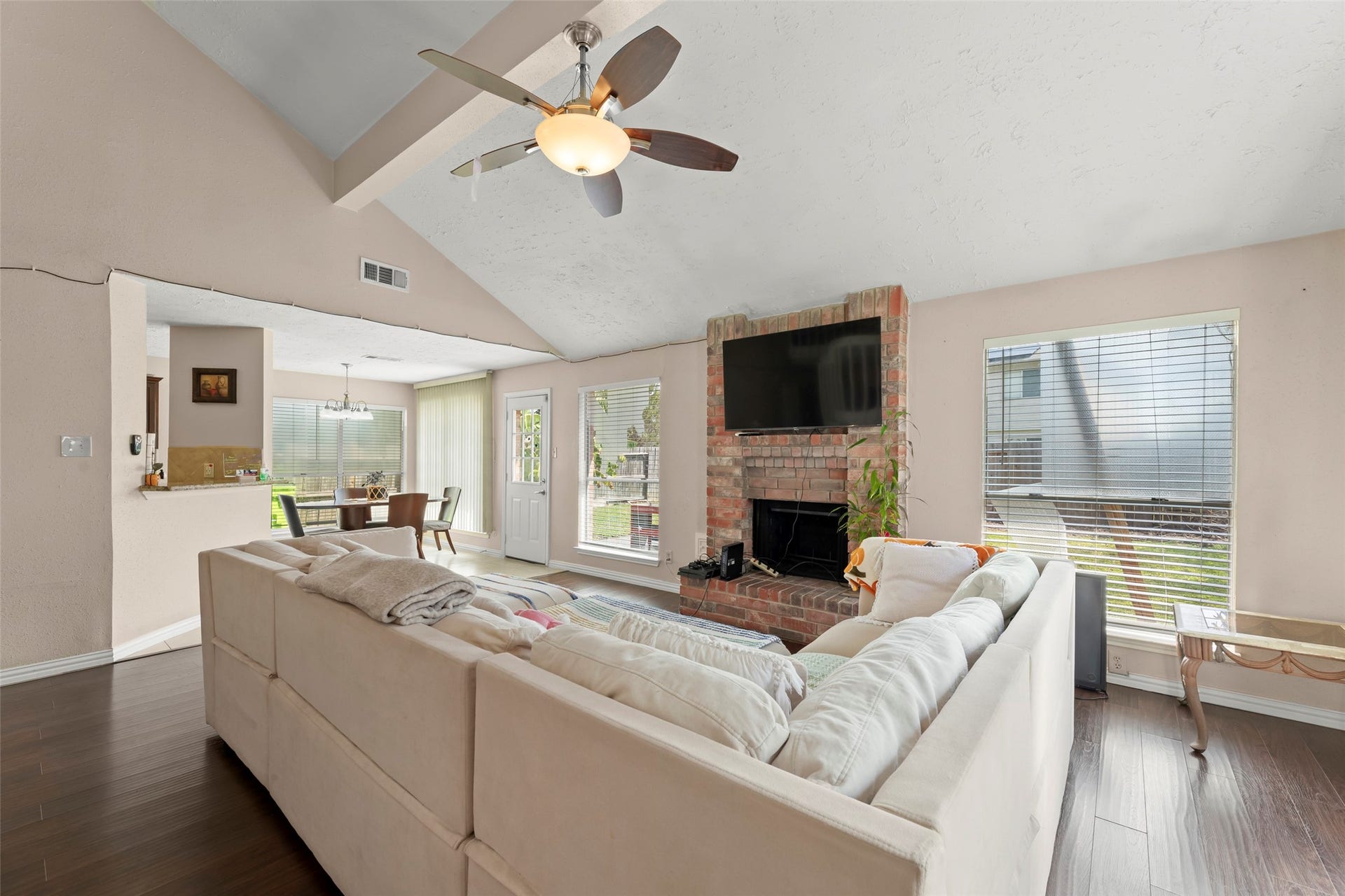 2033 Wildwood Ridge Drive, Missouri City, TX 77489 Open-concept living space showcasing soaring ceilings, a traditional brick hearth, seamless flow into the main living areas, and a lighted ceiling fan.