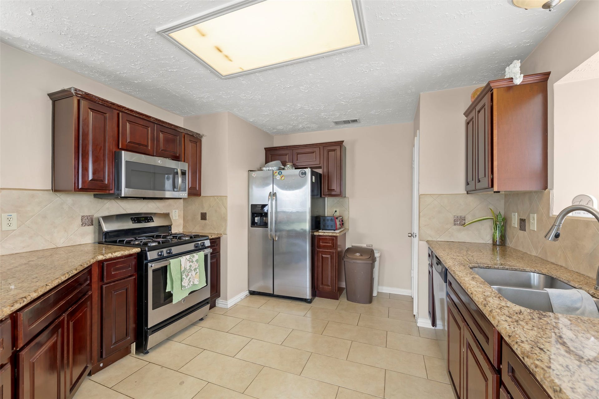 2033 Wildwood Ridge Drive, Missouri City, TX 77489 Kitchen showcasing a suite of contemporary stainless steel appliances, generous cabinet space, and seamless flow into the main living areas.