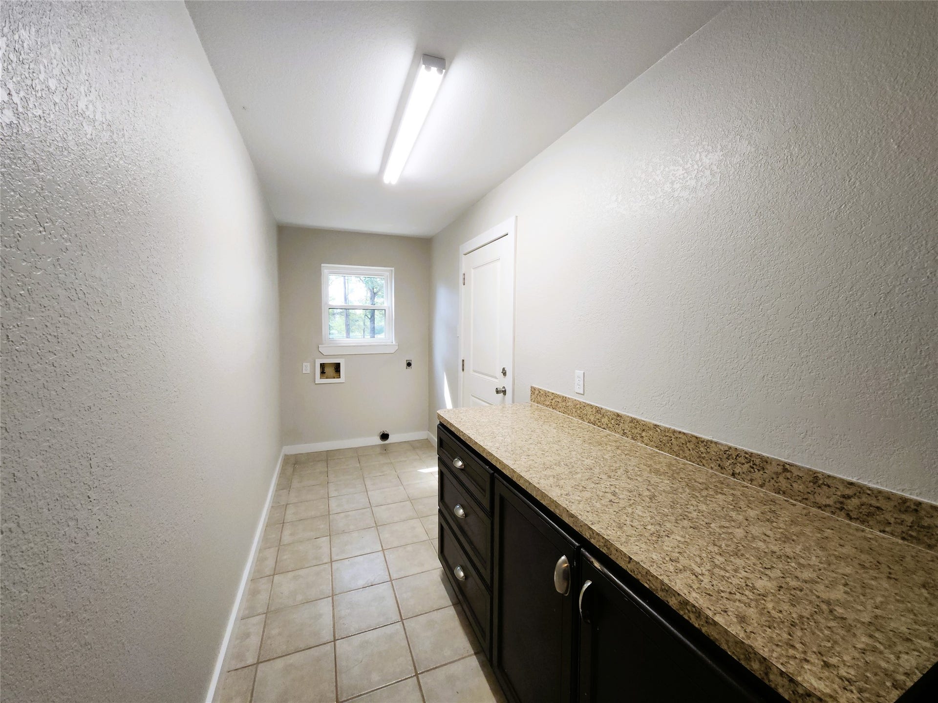 557 Fm 2693 Road E, New Waverly, TX 77358 Spacious laundry room with ample counter space, sleek cabinetry, and natural light through the window, offering functionality and style.