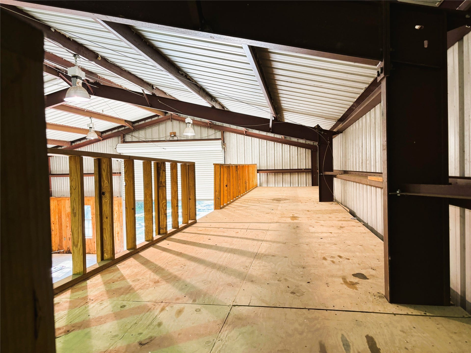 557 Fm 2693 Road E, New Waverly, TX 77358 Spacious interior with high ceilings and natural light, featuring a sturdy wooden mezzanine perfect for storage or versatile use.
