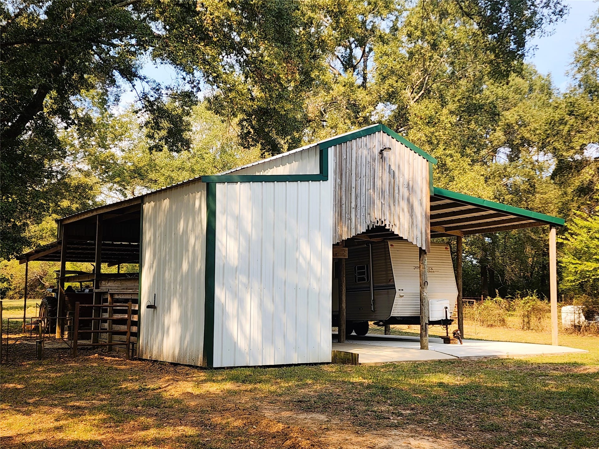 557 Fm 2693 Road E, New Waverly, TX 77358 Spacious barn with covered RV storage, nestled among mature trees for ample shade and privacy.