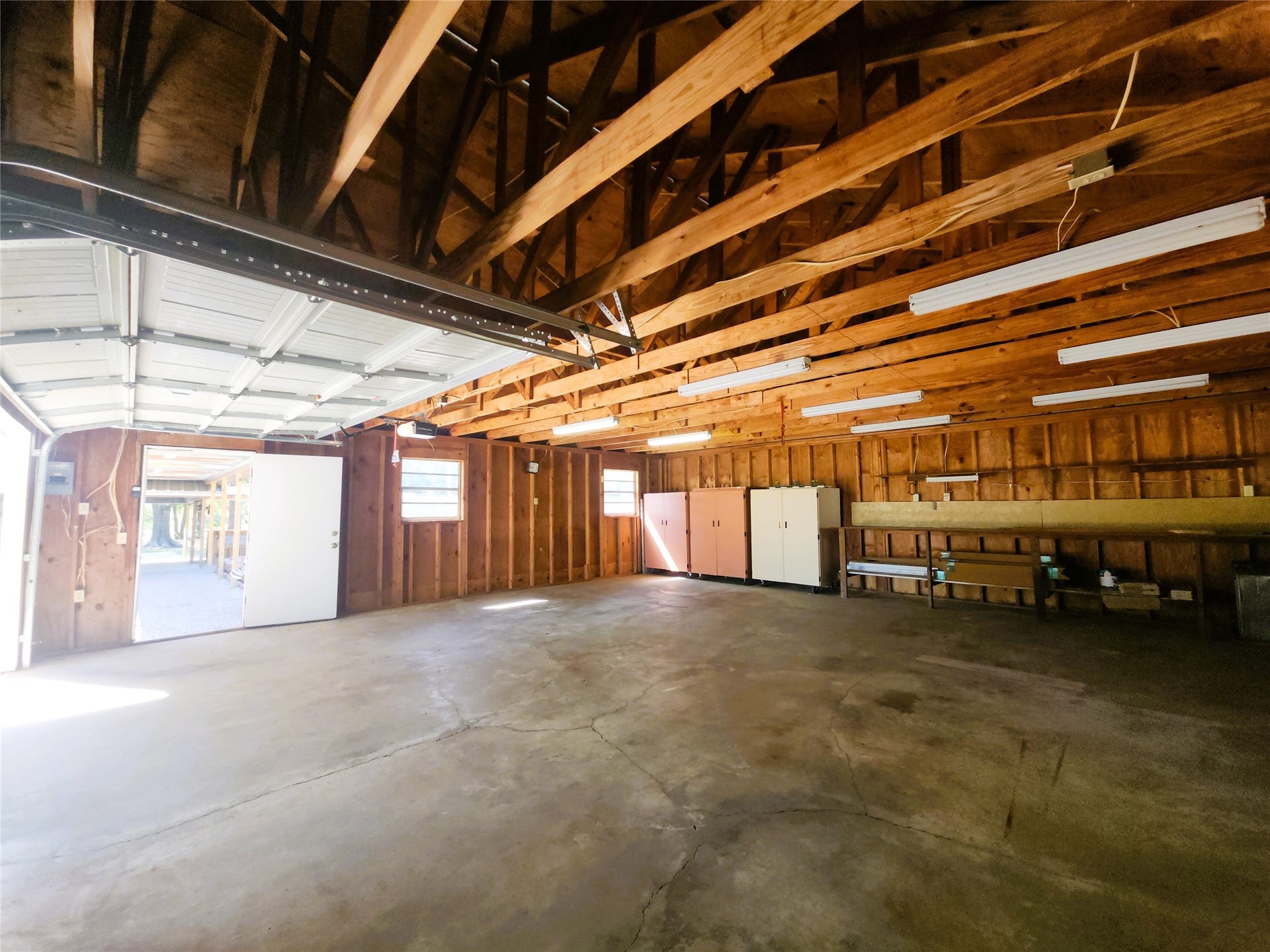 557 Fm 2693 Road E, New Waverly, TX 77358 Spacious 30'x30' detached garage with high ceilings, ample natural light, and plenty of room for storage or workshop activities.