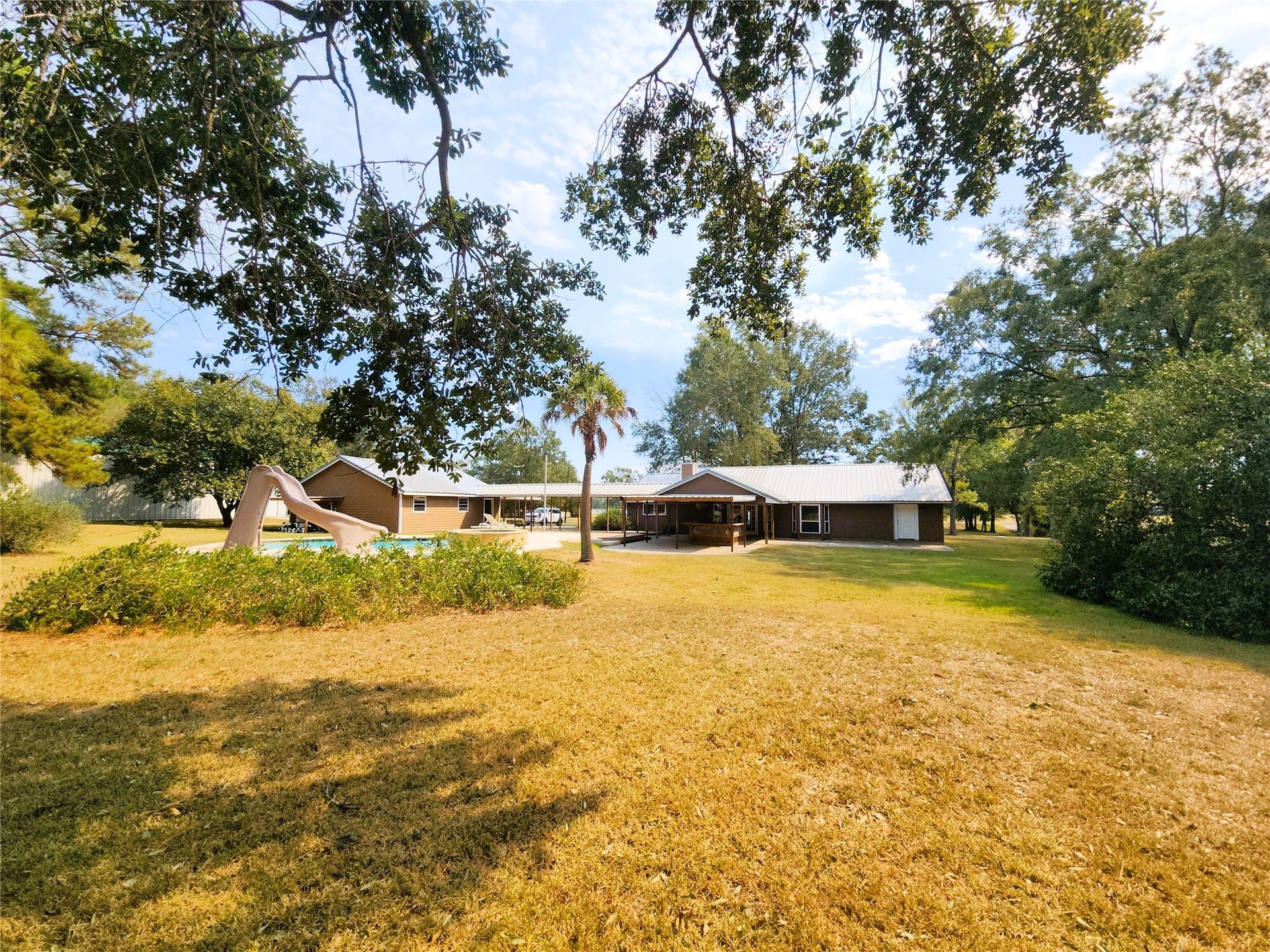 557 Fm 2693 Road E, New Waverly, TX 77358 A view of the backyard, showing the pool, back of the house with covered walk-way over to the detached 3-car garage.