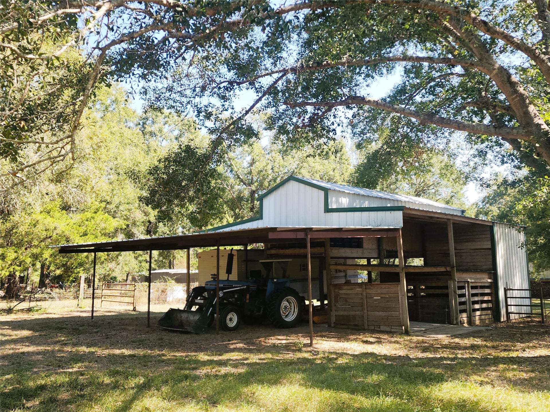 557 Fm 2693 Road E, New Waverly, TX 77358 Charming rural barn with ample storage space, nestled under mature trees, perfect for agricultural use or equipment storage.