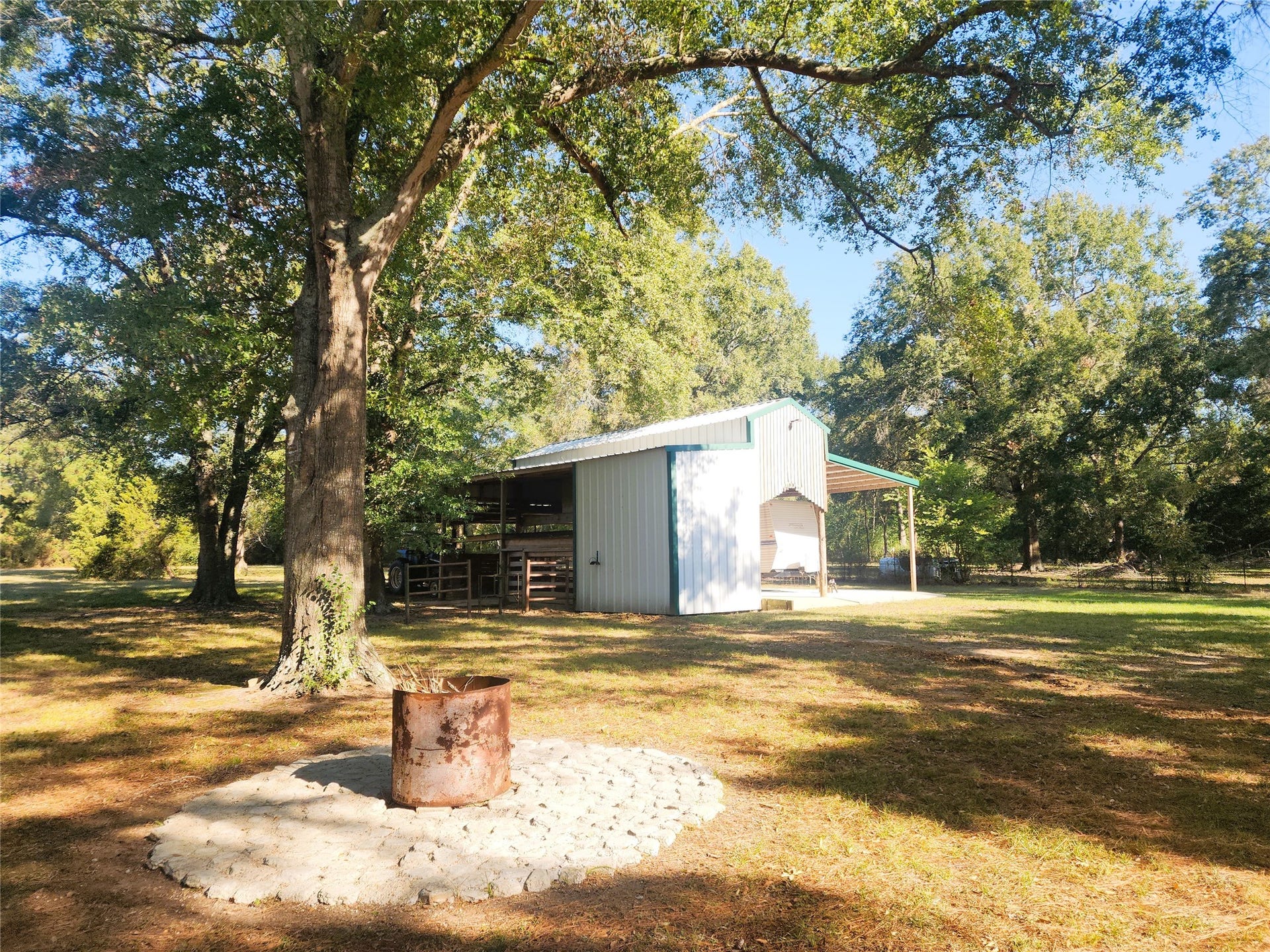 557 Fm 2693 Road E, New Waverly, TX 77358 Expansive outdoor area featuring a rustic fire pit surrounded by mature trees, offering a perfect setting for gatherings and relaxation.