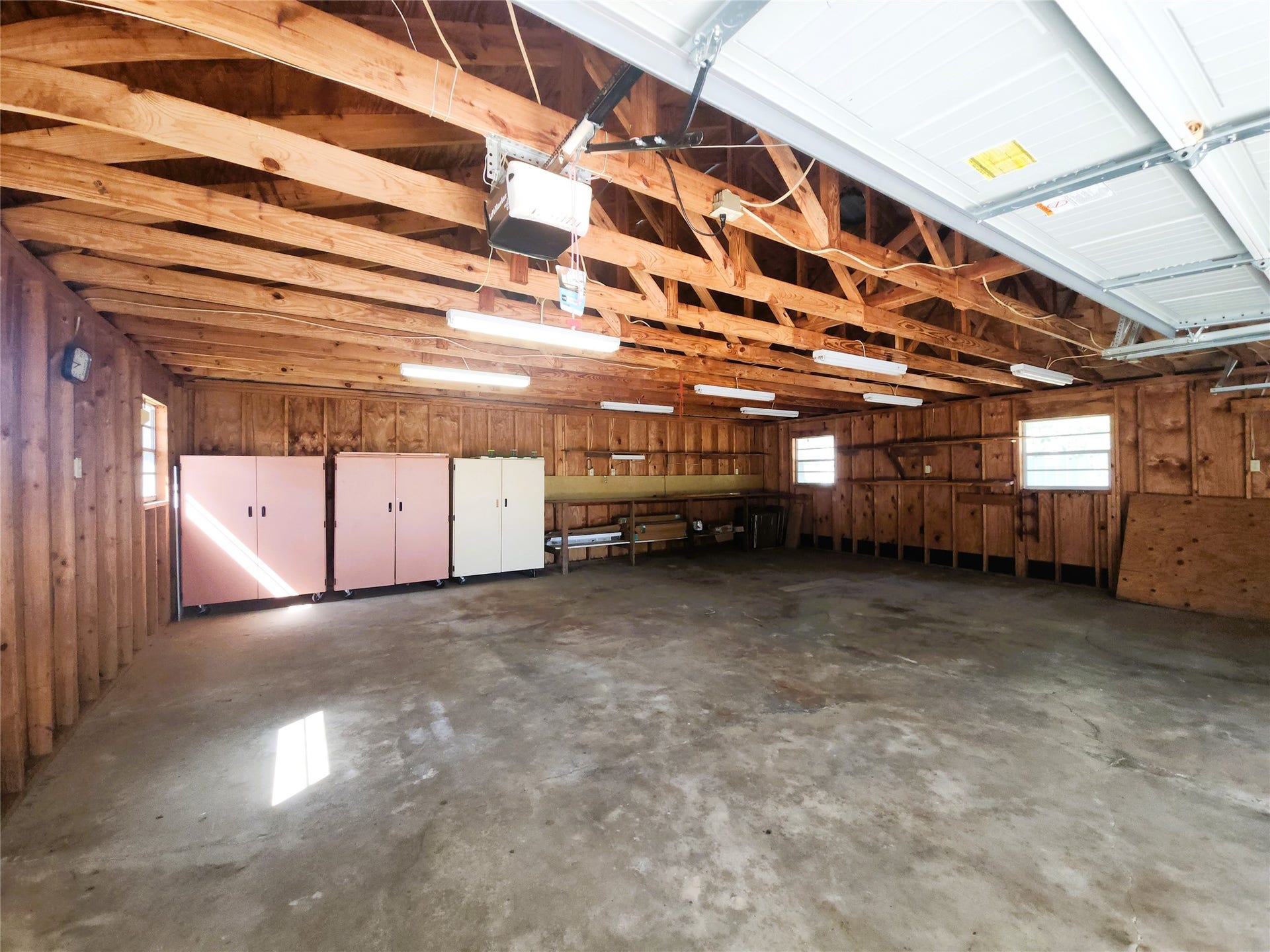 557 Fm 2693 Road E, New Waverly, TX 77358 Spacious garage with ample natural light, featuring exposed beams and storage cabinets, perfect for projects and extra storage.