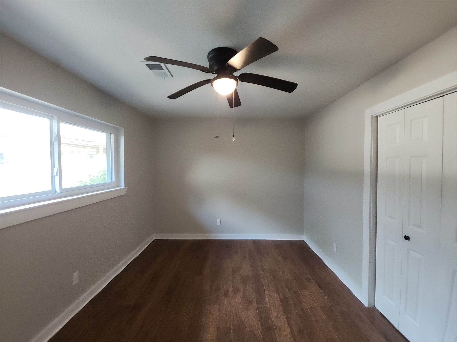 557 Fm 2693 Road E, New Waverly, TX 77358 Bright and inviting bedroom featuring sleek flooring, a modern ceiling fan, ample natural light from a large window, and convenient closet space.
