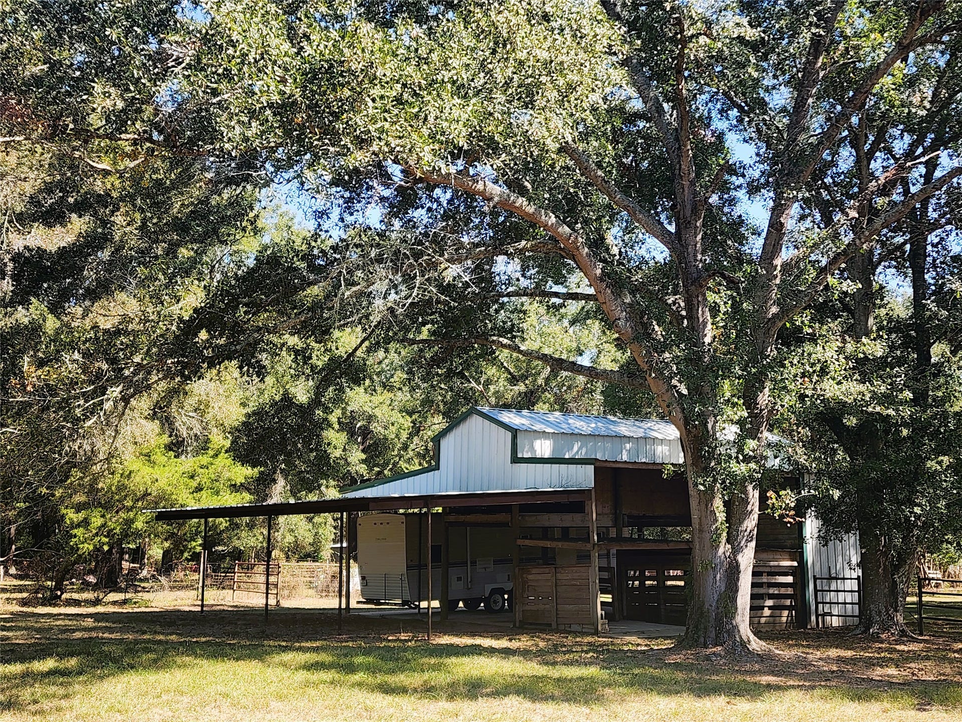557 Fm 2693 Road E, New Waverly, TX 77358 Charming rural property featuring a spacious 36'x36' barn with a 20'x36' lean-to set amidst lush, mature trees, offering ample shade and a serene natural setting.