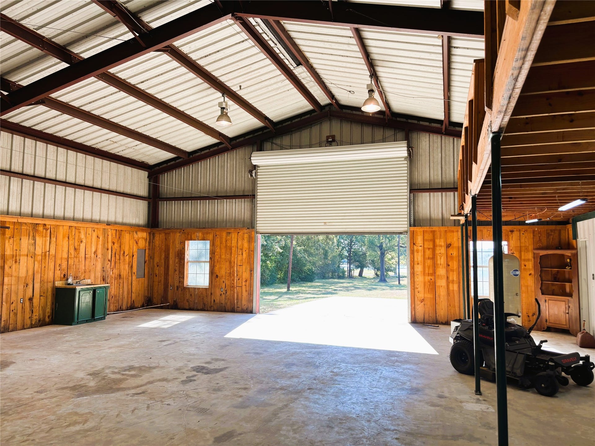 557 Fm 2693 Road E, New Waverly, TX 77358 Spacious metal workshop with high ceilings, roll-up garage door, and natural light, perfect for projects or storage.