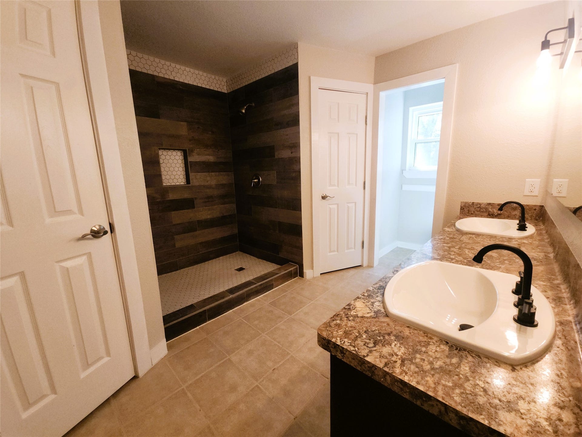 557 Fm 2693 Road E, New Waverly, TX 77358 Spacious bathroom featuring a modern walk-in shower with stylish wood-look tile, dual sinks with elegant fixtures, and ample lighting.