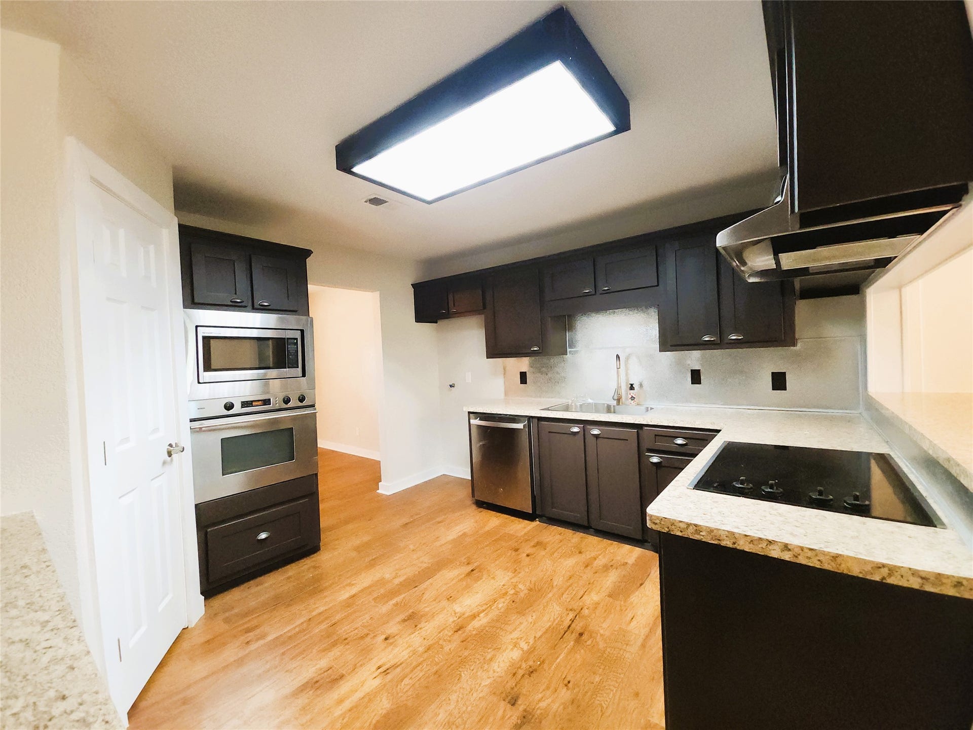 557 Fm 2693 Road E, New Waverly, TX 77358 Kitchen with sleek dark cabinetry, stainless steel appliances, and warm wood flooring, providing a functional and stylish cooking space.