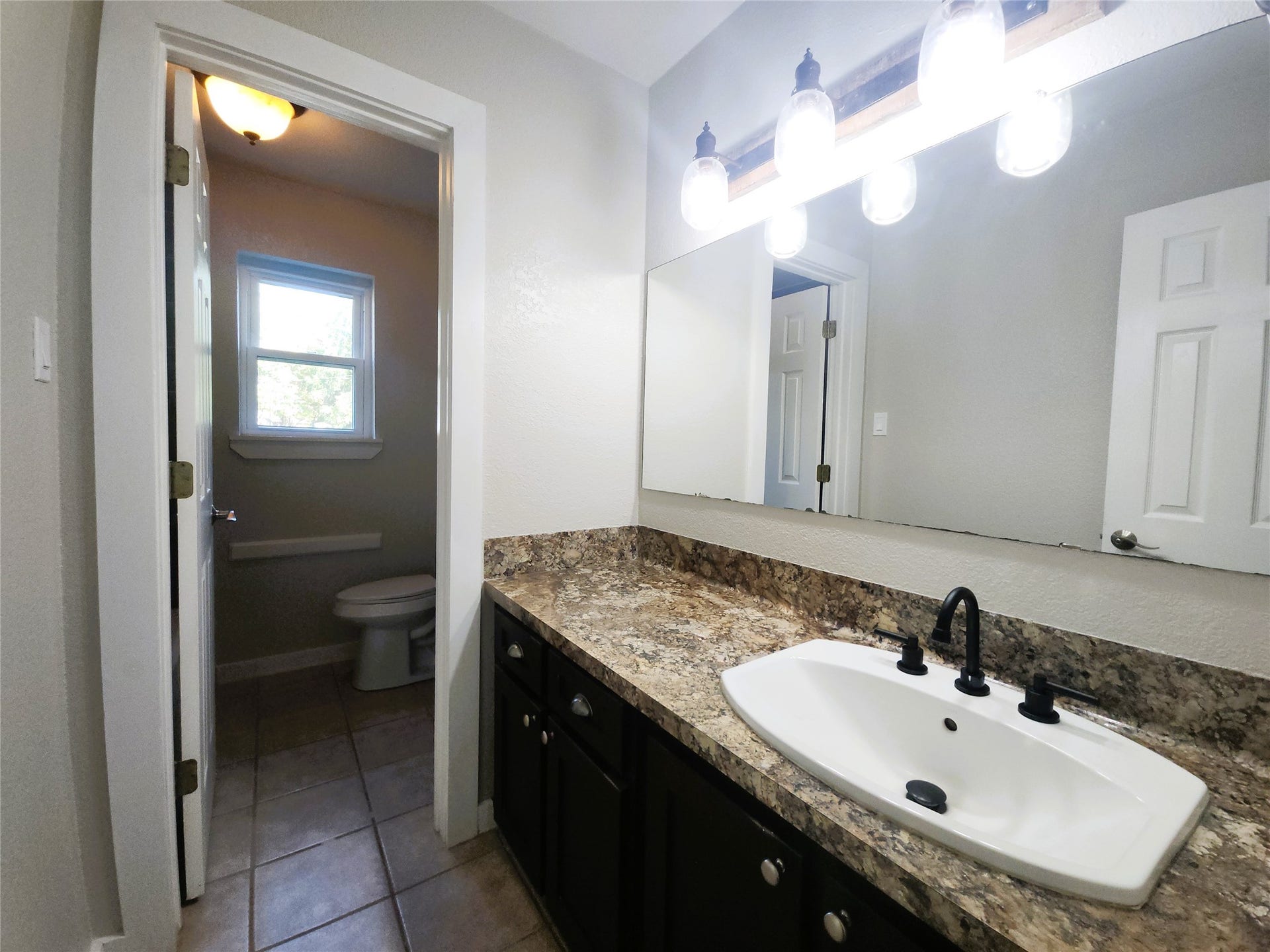 557 Fm 2693 Road E, New Waverly, TX 77358 Secondary bathroom featuring a spacious vanity with a modern sink, complemented by stylish lighting and ample natural light from the adjacent window.