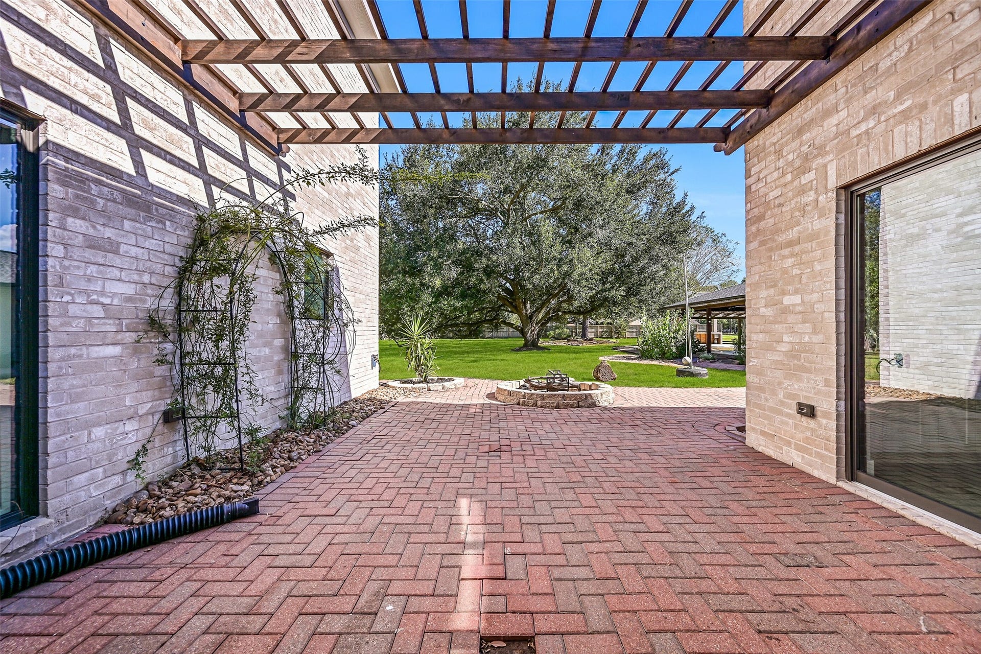 921 Falling Leaf Drive, Friendswood, TX 77546 The paver terrace extends beyond the courtyard to a central fire pit with a beautiful sightline across the expansive backyard to the magnificent century oak. This outdoor space is easily accessed from the family room, breakfast area & primary suite.