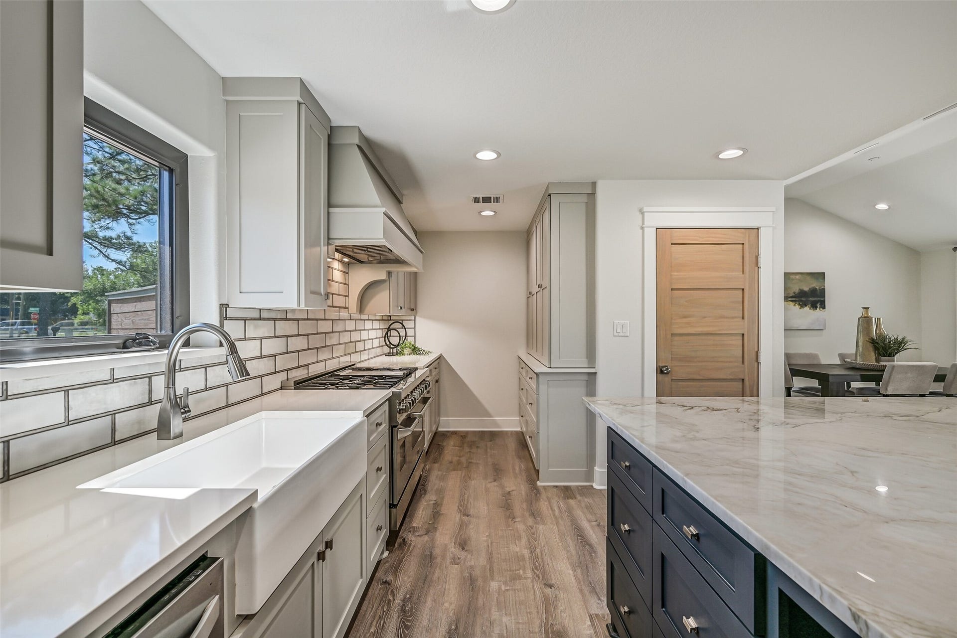 921 Falling Leaf Drive, Friendswood, TX 77546 Thoughtfully designed for function, the kitchen offers an oversized apron-front sink, white quartz perimeter counters & abundant soft-close cabinetry, including a full bank of built-ins with dual powered appliance garages, plus a large walk-in pantry tucked behind the wood door.