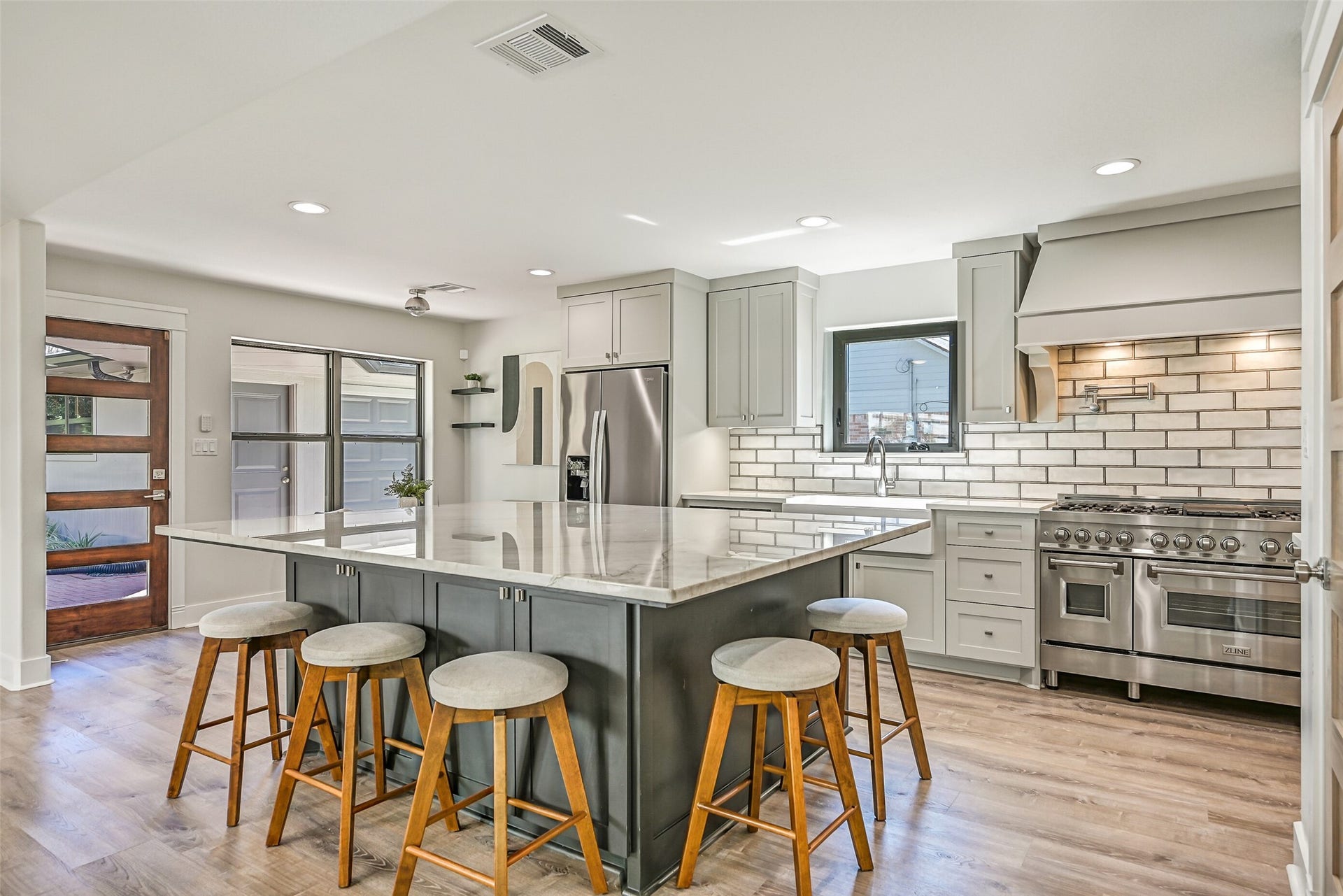 921 Falling Leaf Drive, Friendswood, TX 77546 Designed to gather around, the oversized island offers seating on multiple sides, abundant cabinetry & a gorgeous quartzite surface. Dove gray perimeter cabinetry, a professional-style ZLINE range and custom vent hood complete this thoughtfully redesigned kitchen.