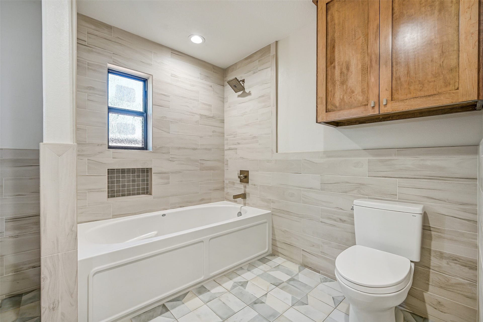 921 Falling Leaf Drive, Friendswood, TX 77546 Wood-look tile wraps the oversized tub/shower and continues halfway up the bathroom walls, complemented by a rainfall-style showerhead, recessed storage niche, privacy window & distinctive marble-look patterned tile flooring