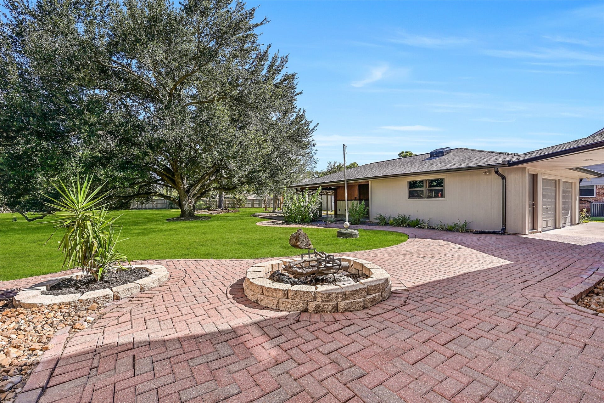 921 Falling Leaf Drive, Friendswood, TX 77546 A circular fire pit anchors the sprawling paver terrace, surrounded by mature landscaping and an incredible amount of lawn. Paver walkways wind toward the detached garage, covered outdoor living areas & the towering trees beyond.