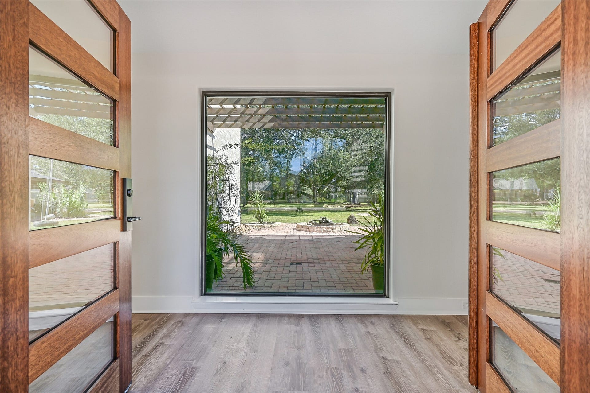 921 Falling Leaf Drive, Friendswood, TX 77546 What an entrance! Double wood-and-glass doors open to a light-filled foyer where an oversized picture window immediately frames the paver terrace, fire pit & magnificent century oak beyond, introducing the homes seamless connection between indoor and outdoor spaces.