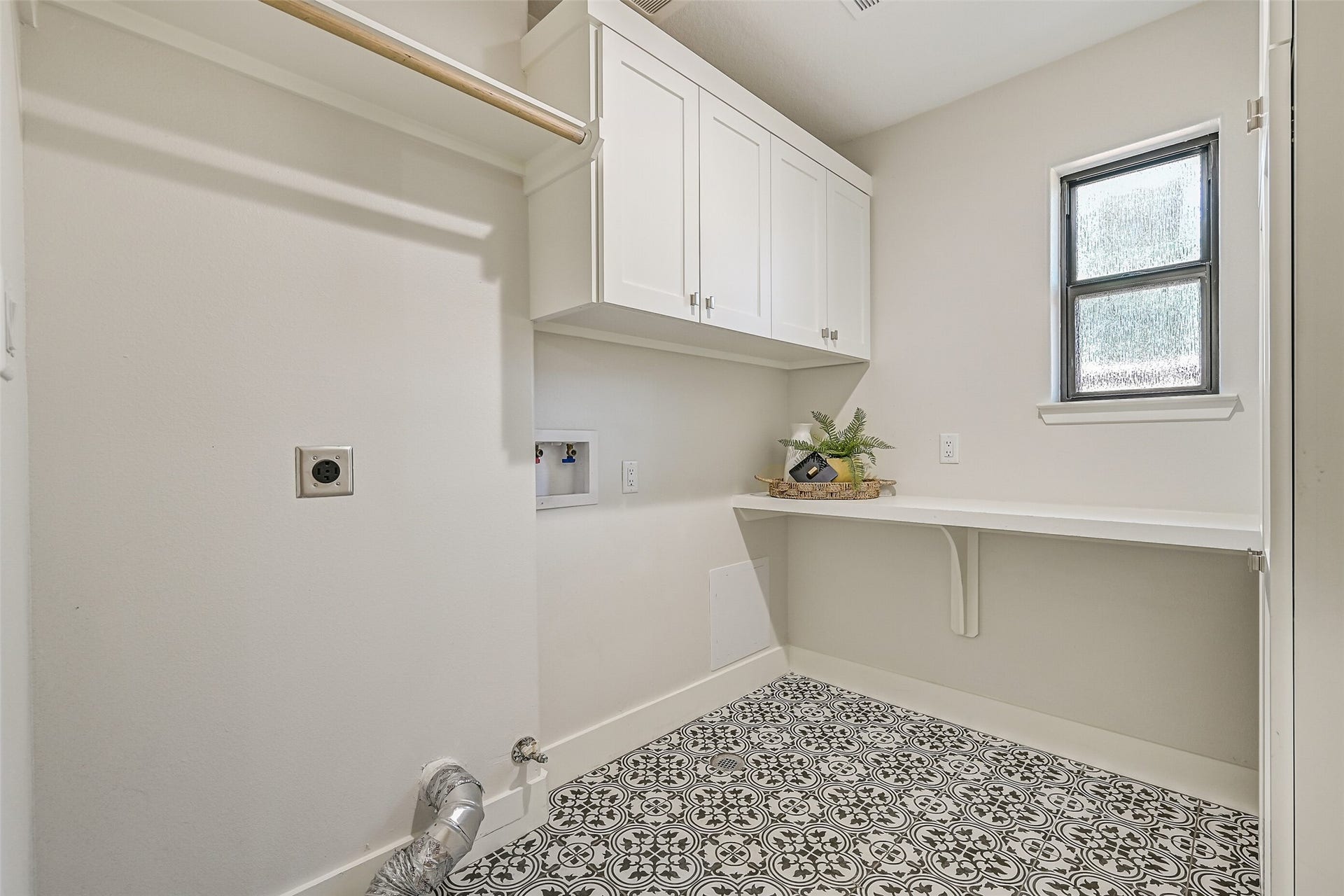 921 Falling Leaf Drive, Friendswood, TX 77546 The 6' x 8' utility room offers a built-in folding counter, abundant upper & tall storage cabinetry, hanging rod, washer/dryer connections and a privacy-glass window for natural light, all finished with eye-catching black & white patterned tile flooring.