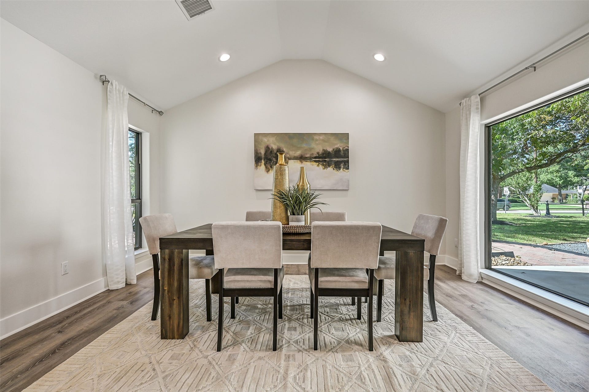 921 Falling Leaf Drive, Friendswood, TX 77546 The open-concept dining room features a vaulted ceiling, recessed lighting, luxury vinyl plank flooring & oversized black-framed windows that fill the space with natural light while complementing the homes clean contemporary design.