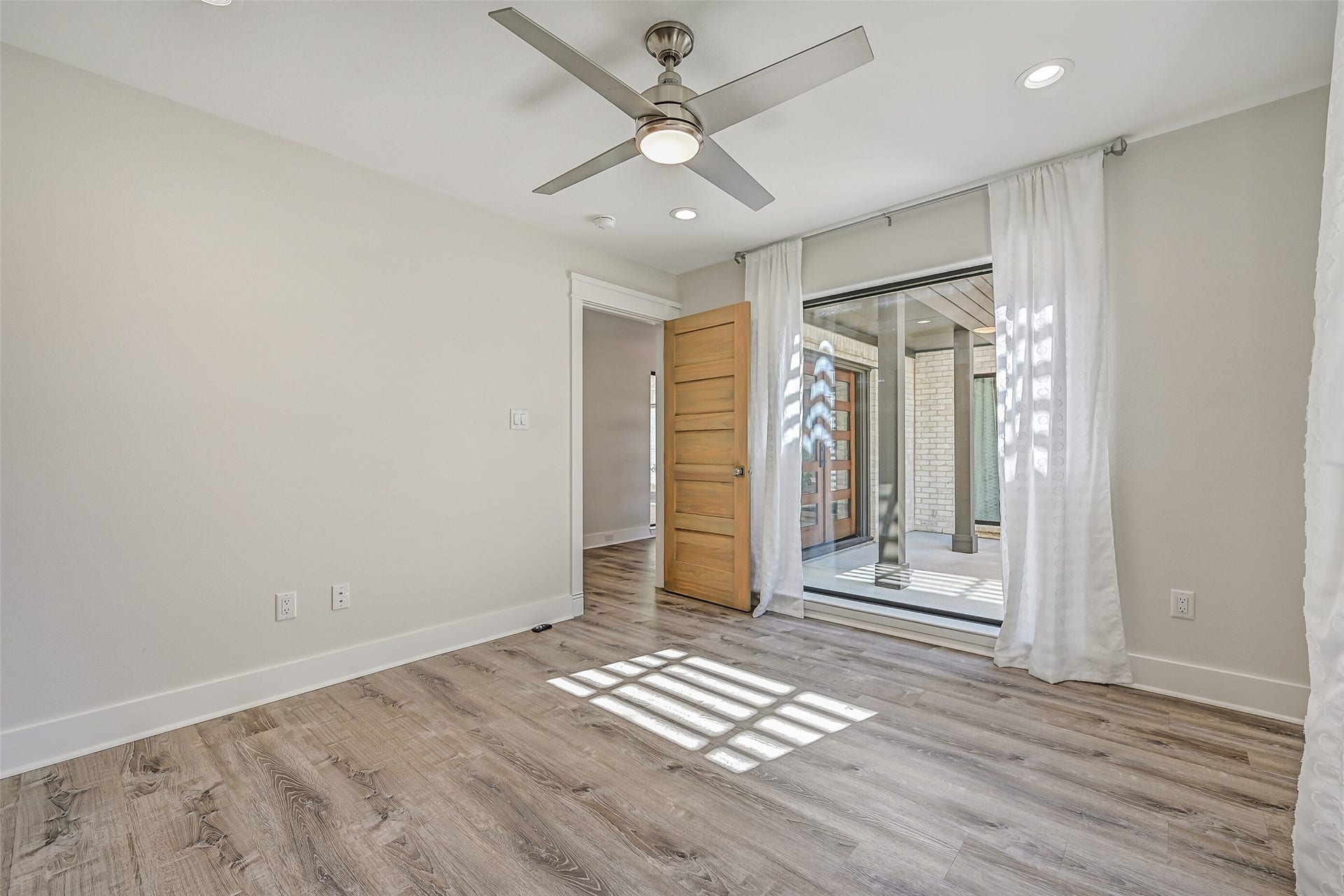 921 Falling Leaf Drive, Friendswood, TX 77546 One of two first-floor secondary bedrooms, this 12' x 11' room offers recessed lighting, a modern lighted ceiling fan, luxury vinyl plank flooring, fresh neutral finishes & a large window overlooking the front entry courtyard.