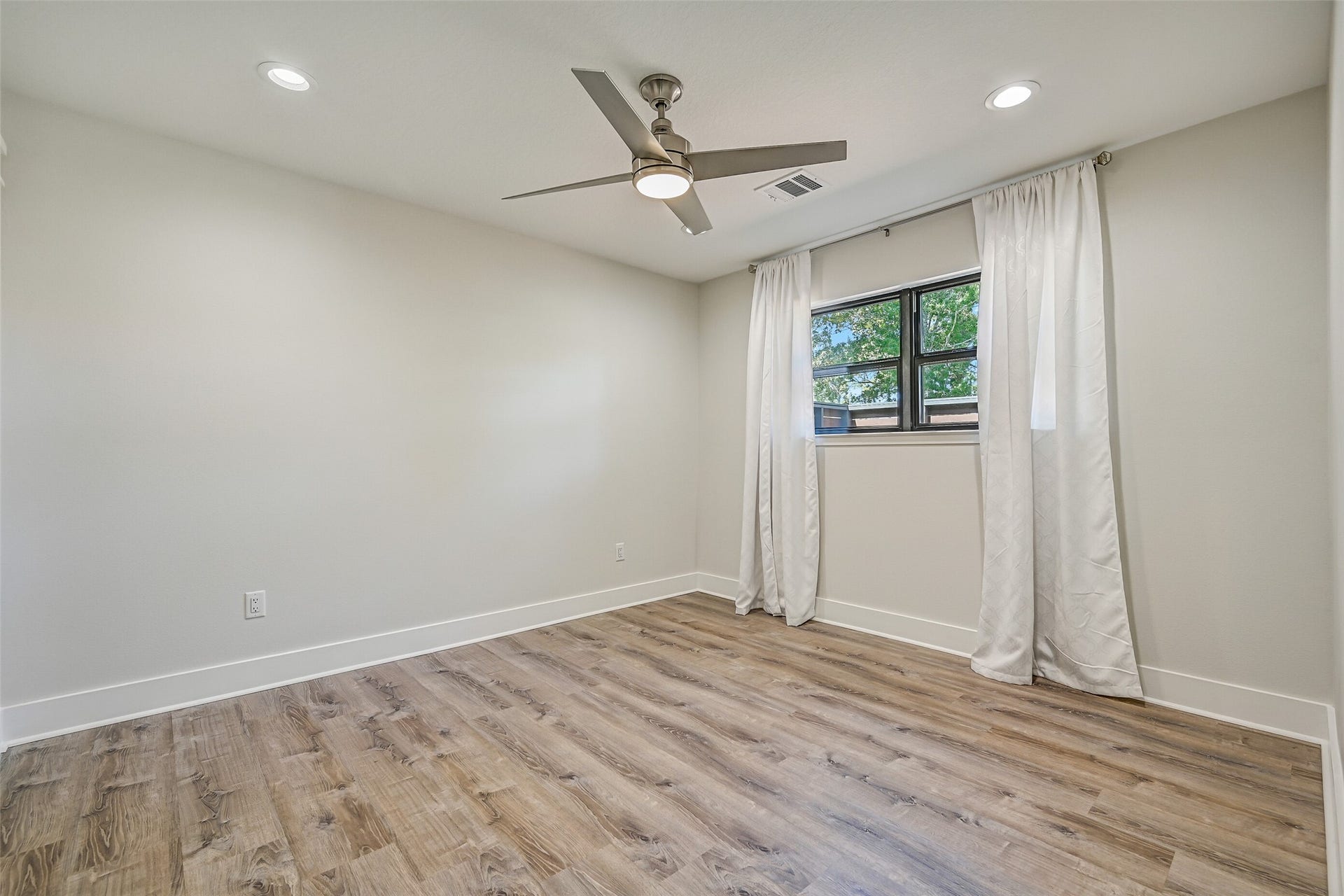 921 Falling Leaf Drive, Friendswood, TX 77546 A second view highlights the clean contemporary finishes of this secondary bedroom, including recessed lighting, luxury vinyl plank flooring, modern lighted ceiling fan & a side-facing window providing natural light.
