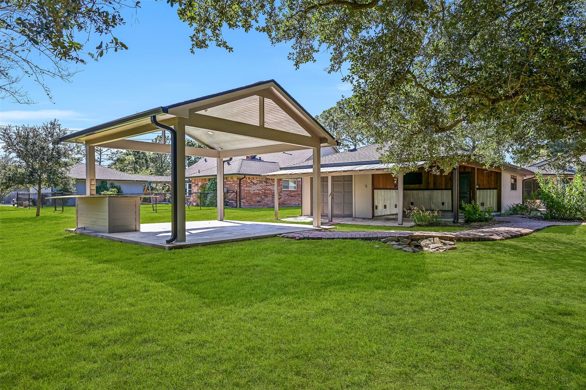 921 Falling Leaf Drive, Friendswood, TX 77546 A separate 17' x 17' open-air pavilion offers even more outdoor living space with a covered concrete slab, recessed lighting and a built-in workstation. The rear door to the lawn equipment/storage bay is visible beyond, providing convenient backyard access.