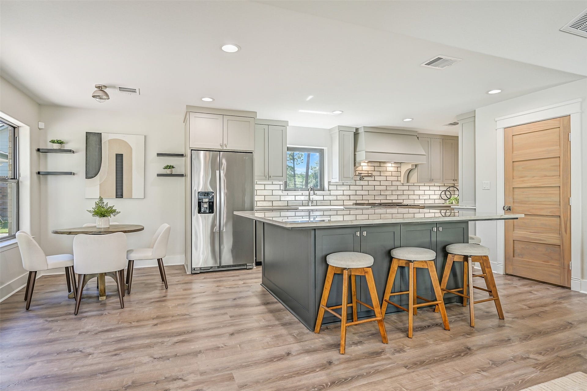 921 Falling Leaf Drive, Friendswood, TX 77546 The impressive 19' x 12' kitchen opens to a sunlit breakfast area and showcases an enormous contrasting island with seating, gorgeous quartzite, soft-close cabinetry, recessed lighting & luxury vinyl plank floors extending throughout the open living space.