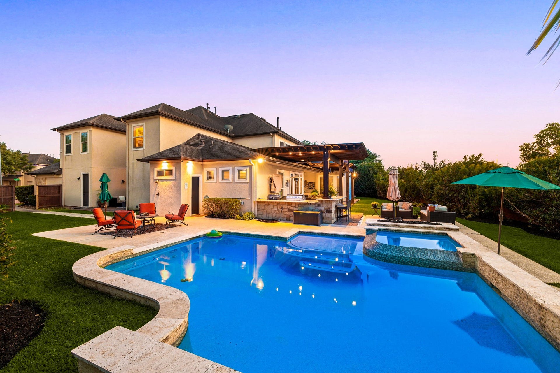 5102 Hawthorne Bend Drive, Katy, TX 77494 Your own backyard paradise! This stunning pool and spa glow beautifully at dusk, surrounded by a travertine deck, lush landscaping, covered pergola, and outdoor kitchen, resort-style living every single day!