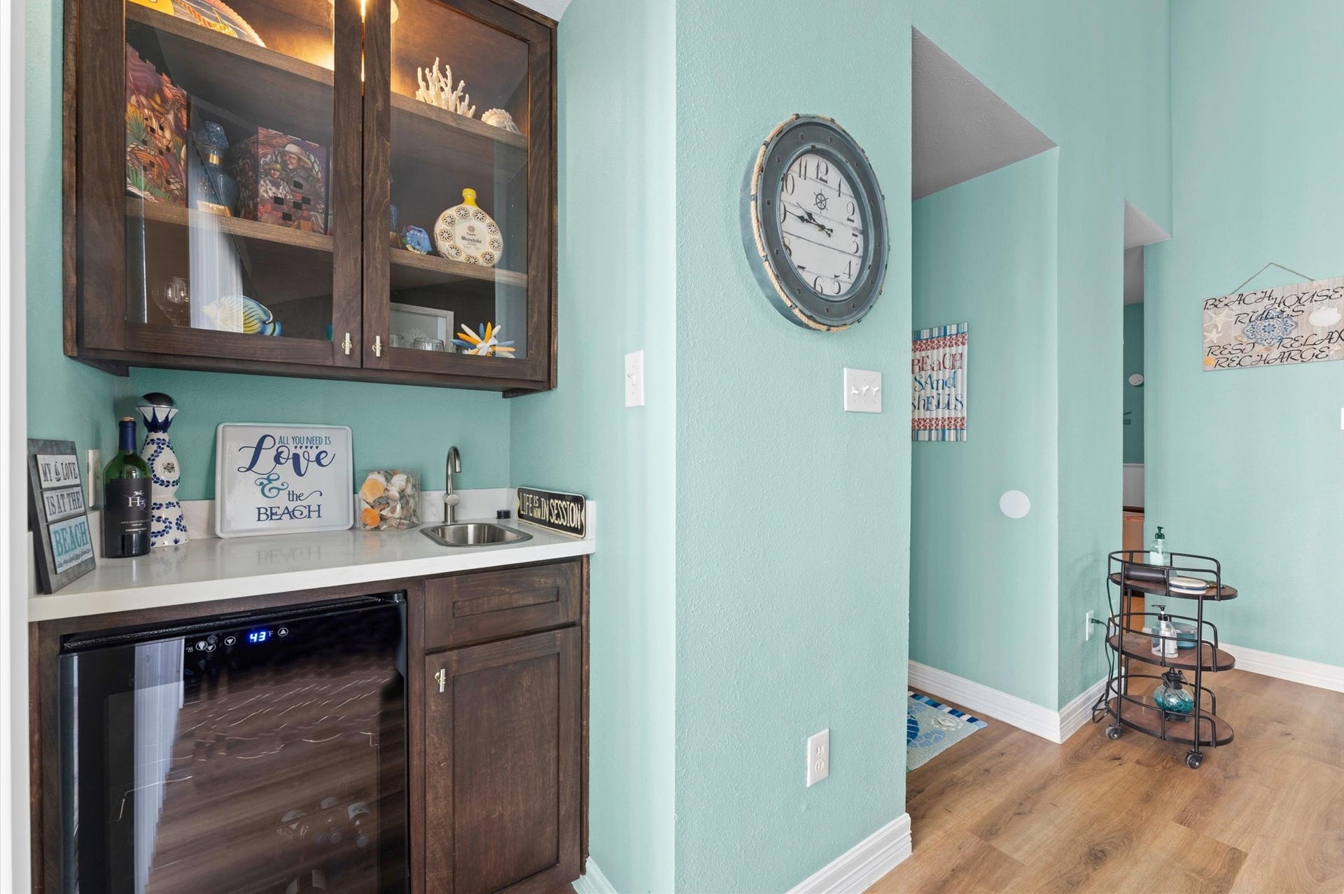 Cozy wet bar area, with sink, fridge, and fresh, upscale custom cabinetry and lighting.
