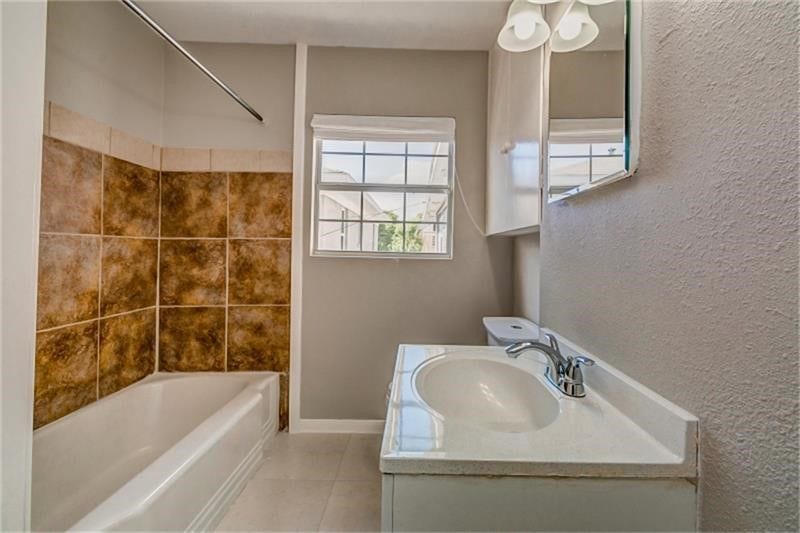 3502 Rosedale Street, Houston, TX 77004 Bright bathroom with a tiled tub-shower combo, modern vanity, and ample natural light from the window.