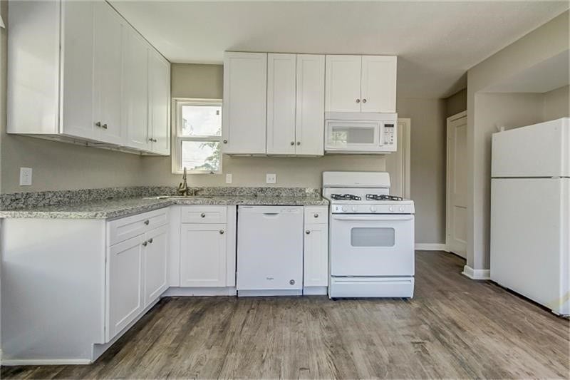 3502 Rosedale Street, Houston, TX 77004 Kitchen with sleek white cabinetry, modern appliances, and elegant granite countertops, complemented by stylish wood-look flooring.