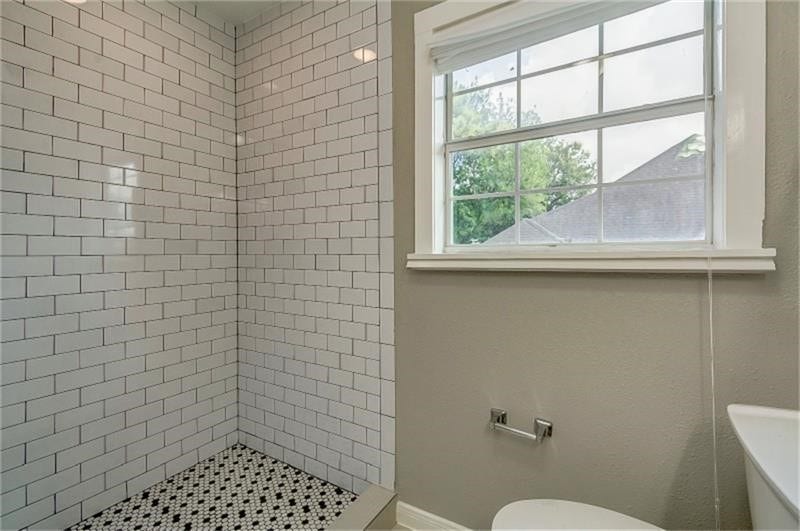 3502 Rosedale Street, Houston, TX 77004 Classic subway-tiled shower and a window with a picturesque view, allowing natural light to brighten the space.