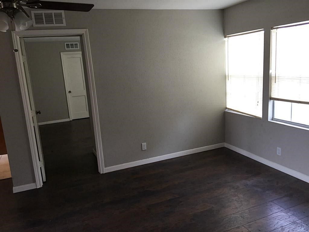 3502 Rosedale Street, Houston, TX 77004 Room with dark hardwood floors, neutral walls, and ample natural light from large windows, offering a welcoming and versatile space.