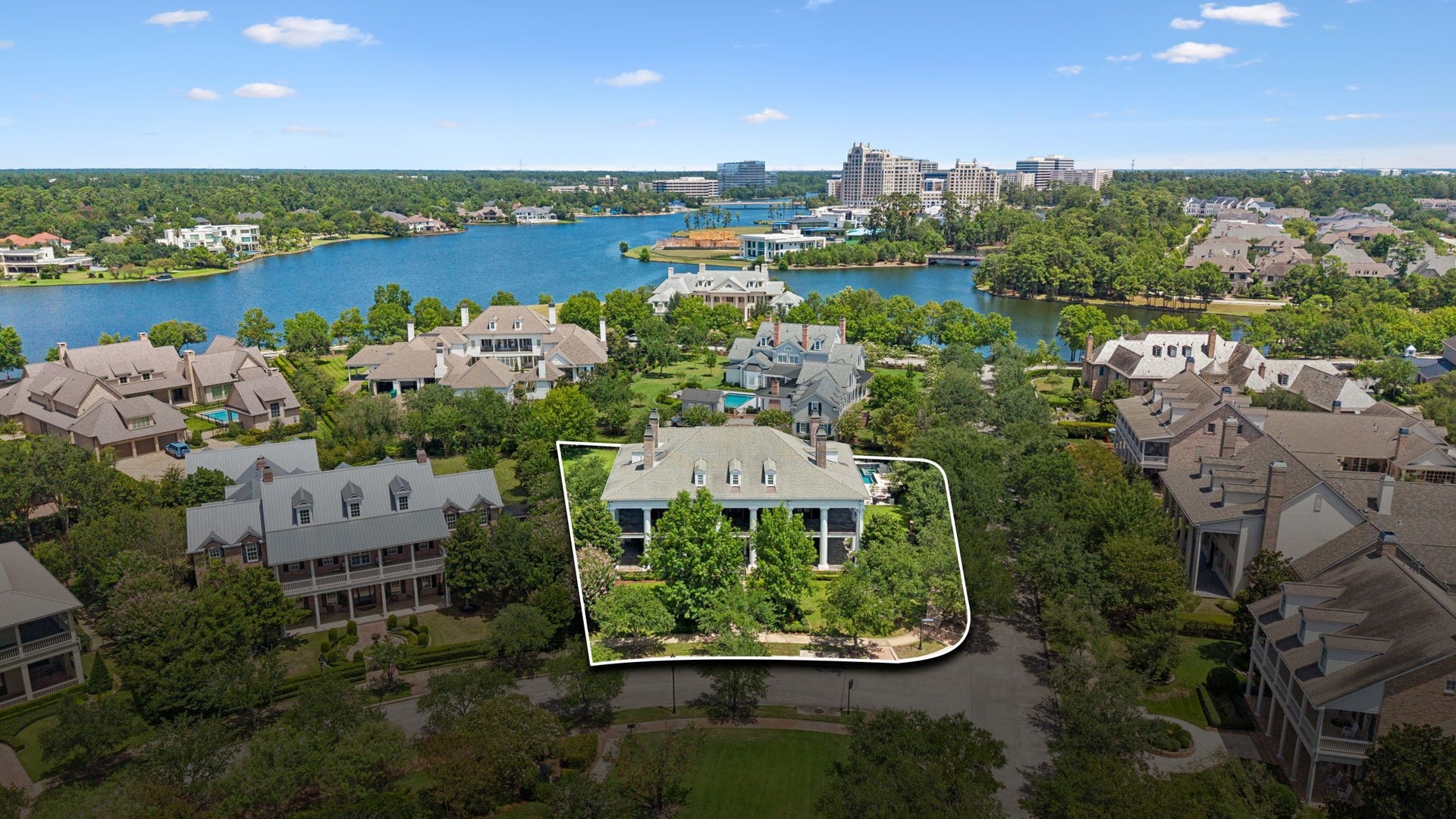 2 Georgian Row, The Woodlands, TX 77380 An exceptional setting in one of the areas most distinctive residential enclaves. This aerial view showcases the propertys substantial footprint and proximity to the lake, surrounded by impressive estate homes, mature greenery, and a picturesque waterfront landscape.