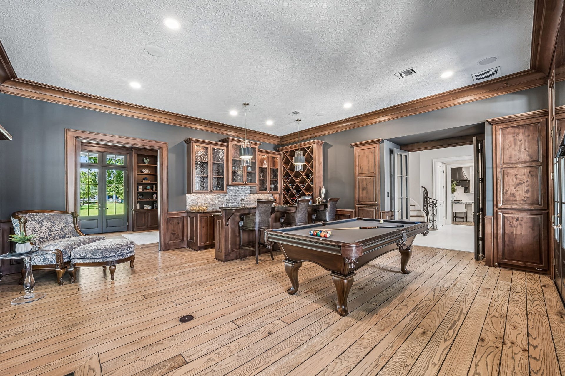 2 Georgian Row, The Woodlands, TX 77380 Spacious game and entertainment room featuring rich wood detailing, a built-in bar with wine storage, and ample space for billiards and gathering. The natural wood floor is throughout this beautiful home.