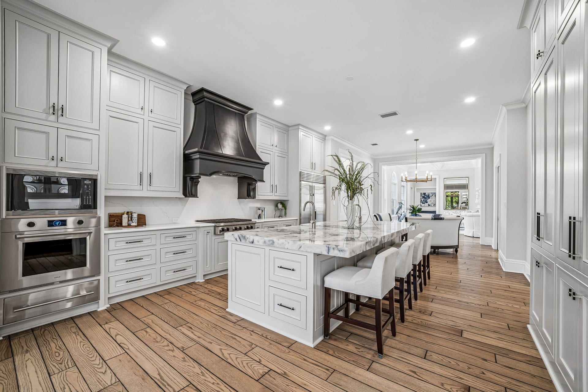 2 Georgian Row, The Woodlands, TX 77380 Expansive main kitchen centered around an oversized authentic quartzite-topped island with generous seating, custom cabinetry, professional-style appliances, and a striking statement range hood.