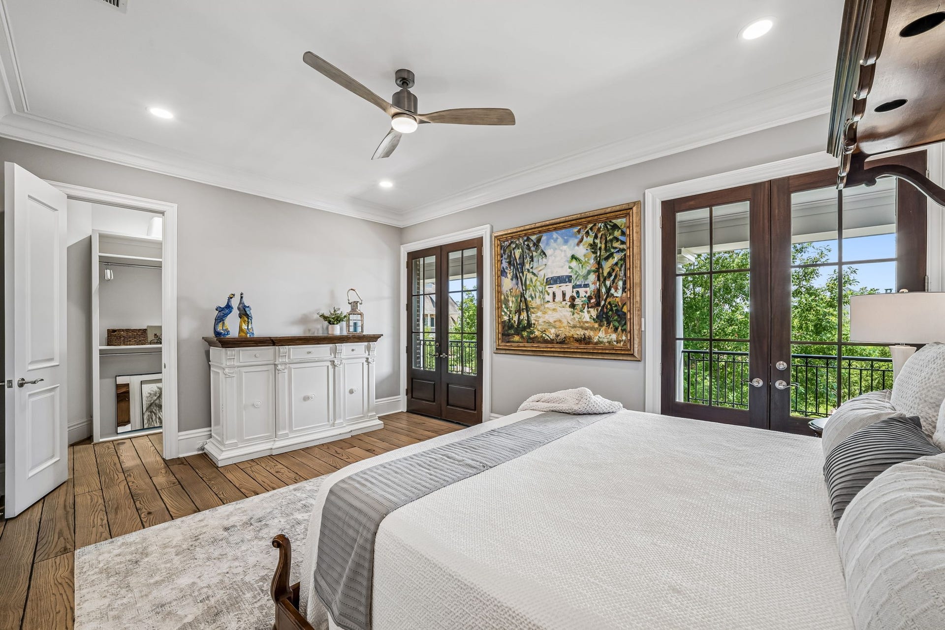 2 Georgian Row, The Woodlands, TX 77380 Beautifully appointed bedroom featuring hardwood floors, crown molding, recessed lighting, ceiling fan, walk-in closet, and two sets of French doors opening to the veranda and filling the room with natural light.