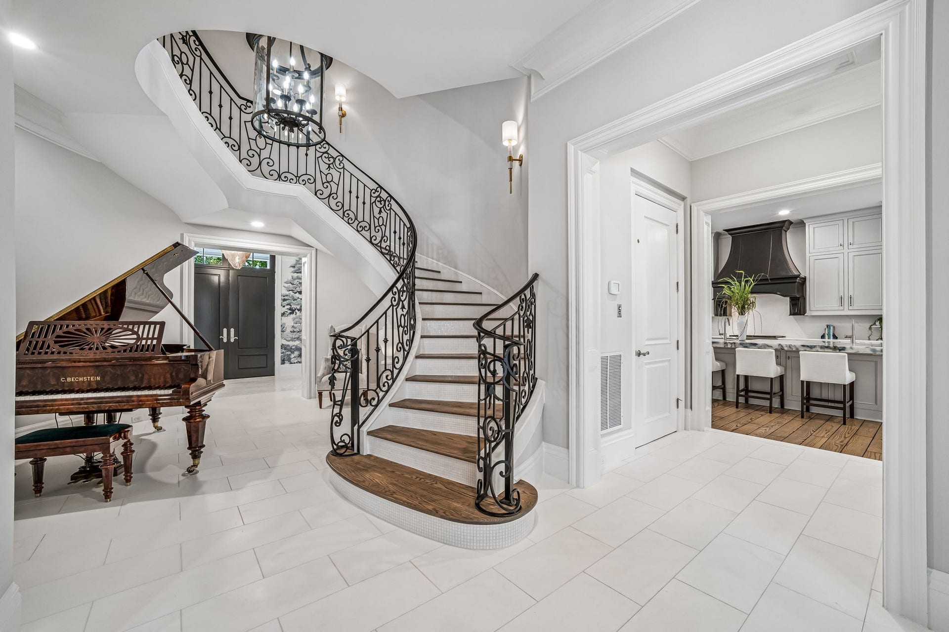 2 Georgian Row, The Woodlands, TX 77380 A sweeping spiral staircase serves as an architectural centerpiece, framed by intricate wrought-iron railings and White Thassos mosaic marble detailing along the staircase face.