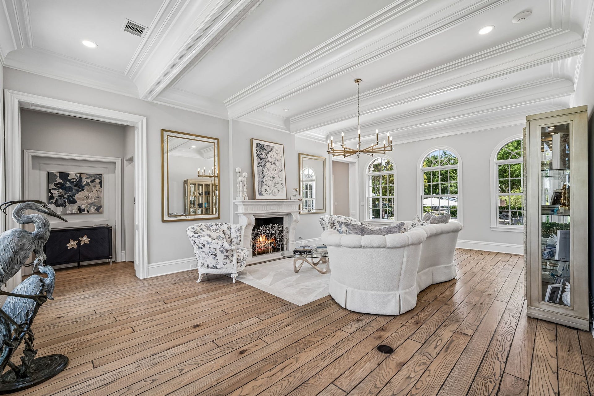 2 Georgian Row, The Woodlands, TX 77380 Beautifully appointed formal living room featuring dramatic coffered ceilings, extensive custom millwork, arched windows, hardwood flooring, and a stone fireplace that serves as the centerpiece of the room.