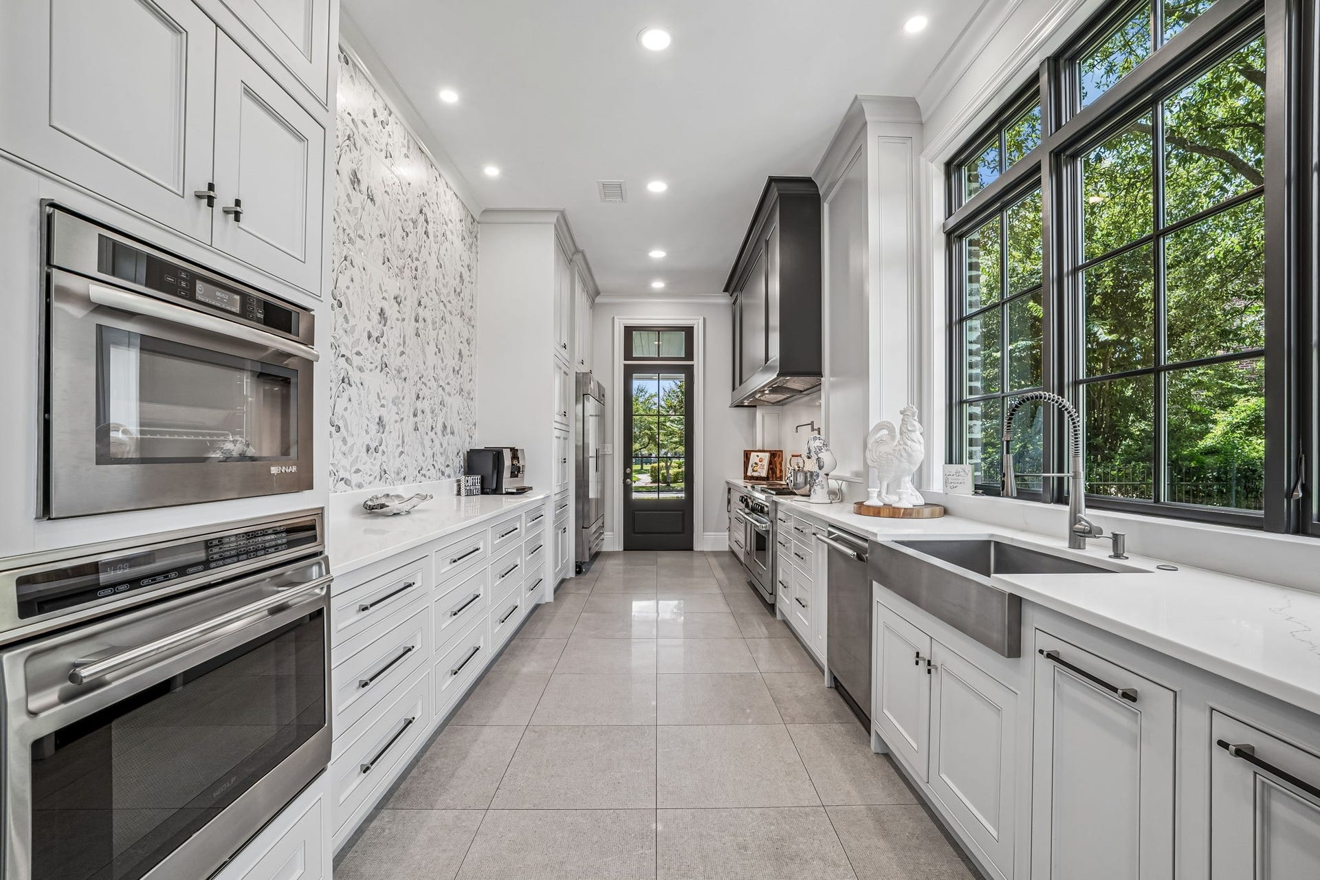 2 Georgian Row, The Woodlands, TX 77380 A fully equipped secondary chefs kitchen offers a separate catering entrance, extensive custom cabinetry, multiple ovens, commercial grade appliances, warming drawers, and a separate catering entrance. The wall is Italian tile.