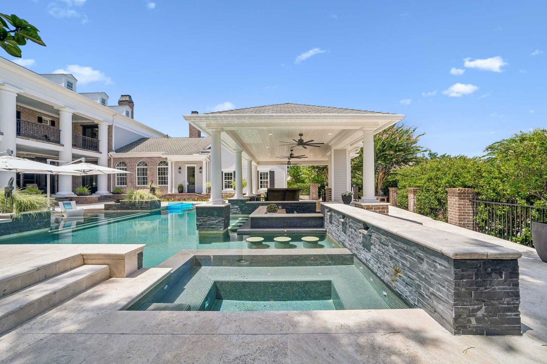 2 Georgian Row, The Woodlands, TX 77380 Exceptional craftsmanship is on display throughout this custom-designed poolscape, featuring an elevated spa, multiple water features, submerged seating, integrated bar stools, and extensive stonework.