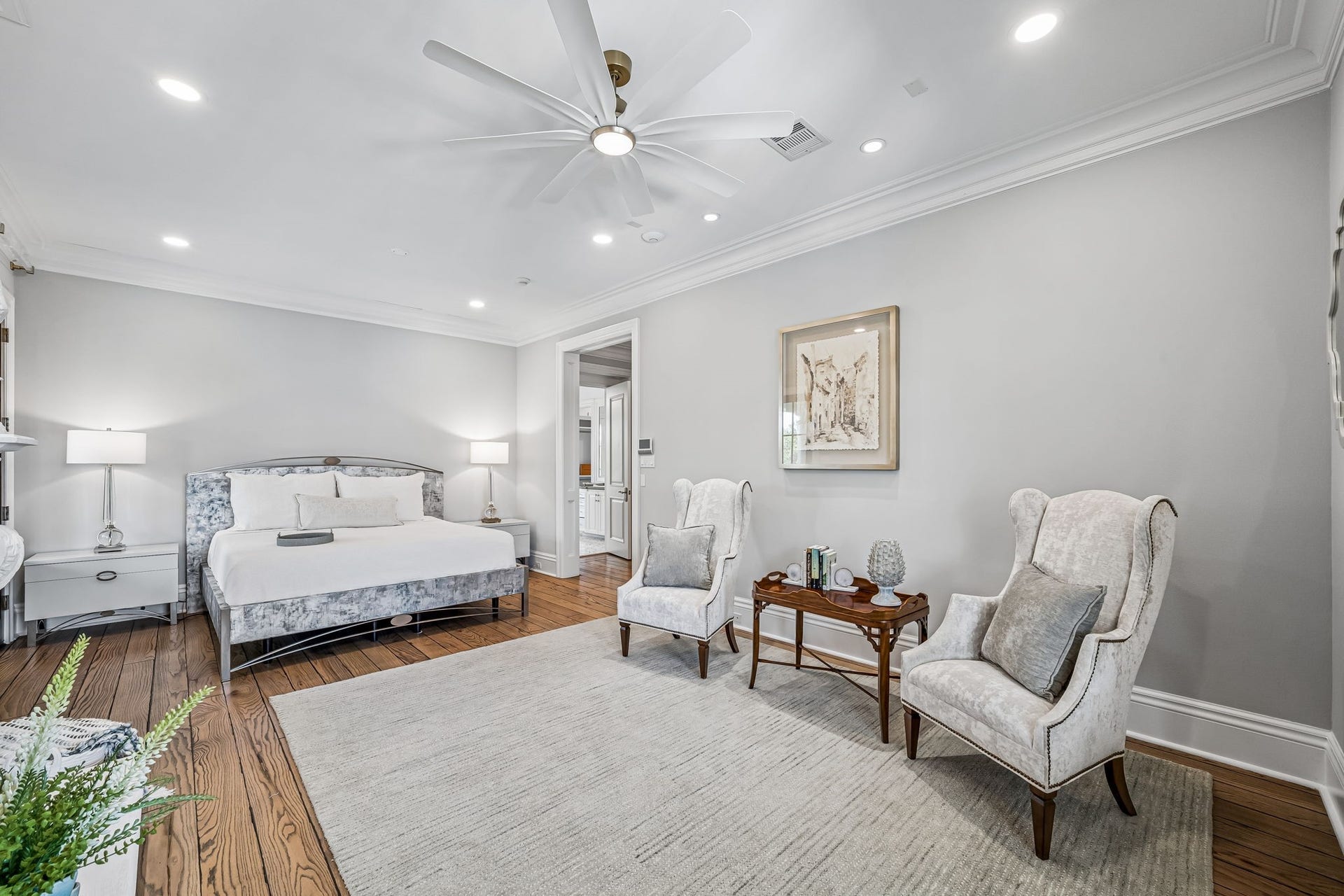 2 Georgian Row, The Woodlands, TX 77380 The primary bedroom offers exceptional space for both a full bedroom arrangement and dedicated sitting area, complemented by hardwood floors, layered crown molding, recessed lighting, and a private fireplace.