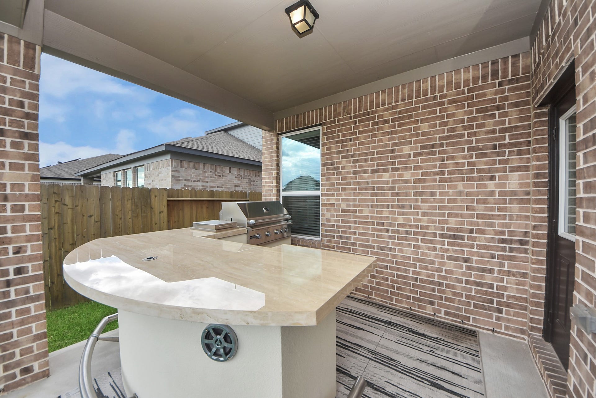 Charming outdoor space featuring a covered patio with a built-in grill and bar area, perfect for entertaining.