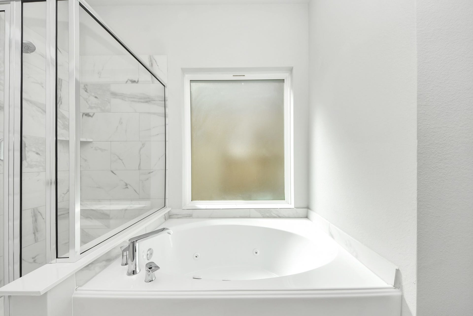 This bathroom featuring a sleek glass-enclosed shower and a spacious soaking tub, complemented by a large frosted window for natural light and privacy.